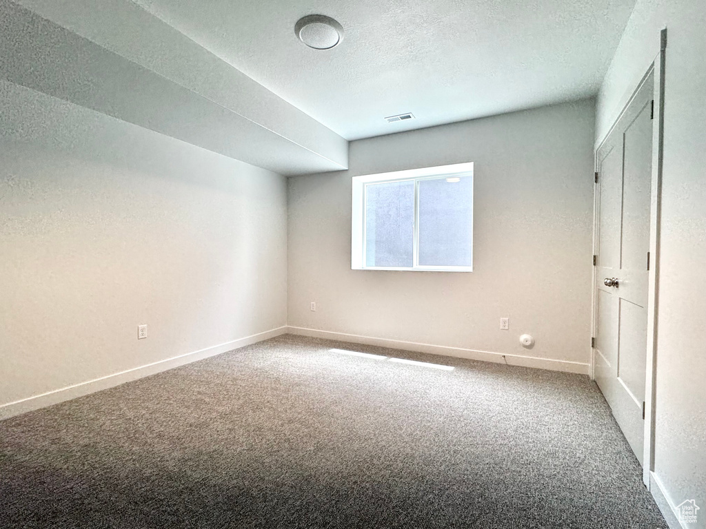 Unfurnished bedroom with carpet, baseboards, and a textured ceiling