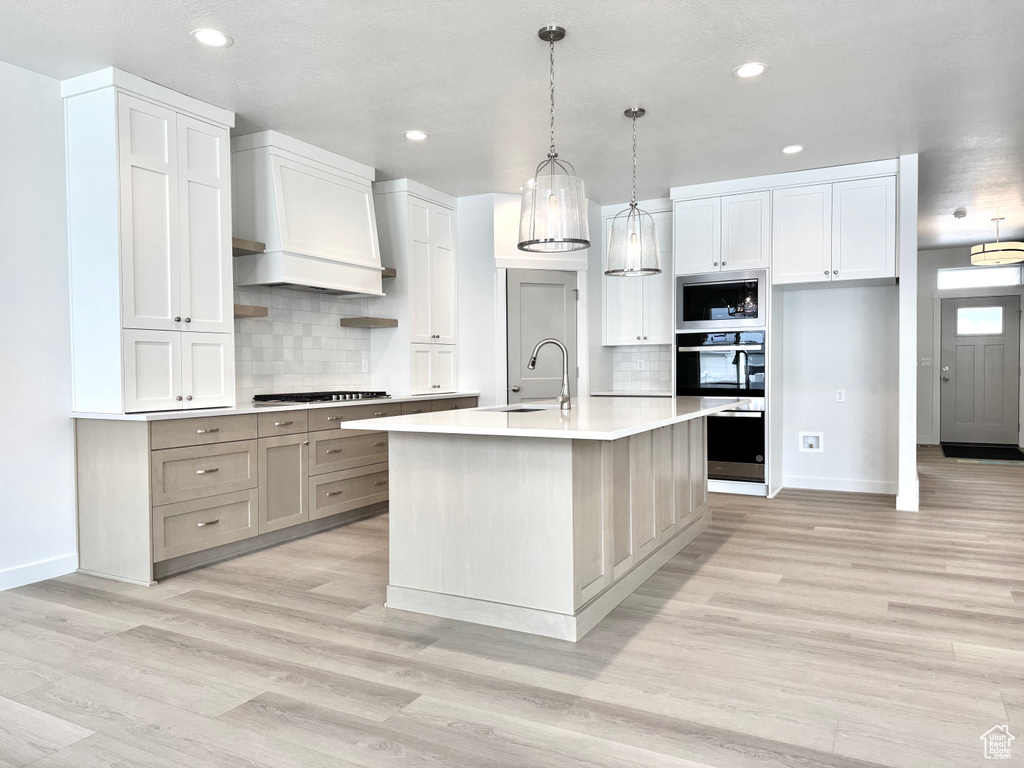 Kitchen with a sink, baseboards, stainless steel appliances, light wood-style flooring, and recessed lighting