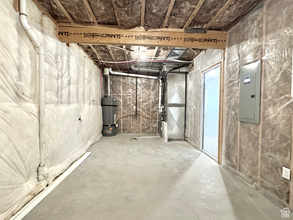 Unfinished below grade area featuring electric panel, secured water heater, and heating unit