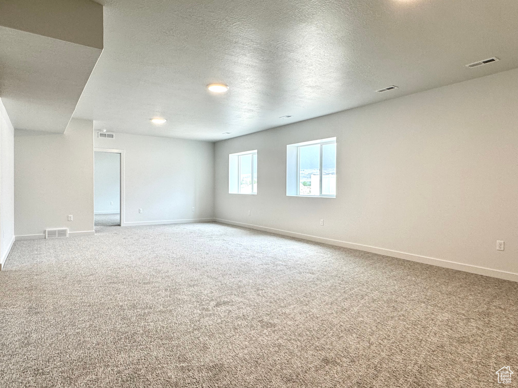 Empty room with carpet, baseboards, and a textured ceiling