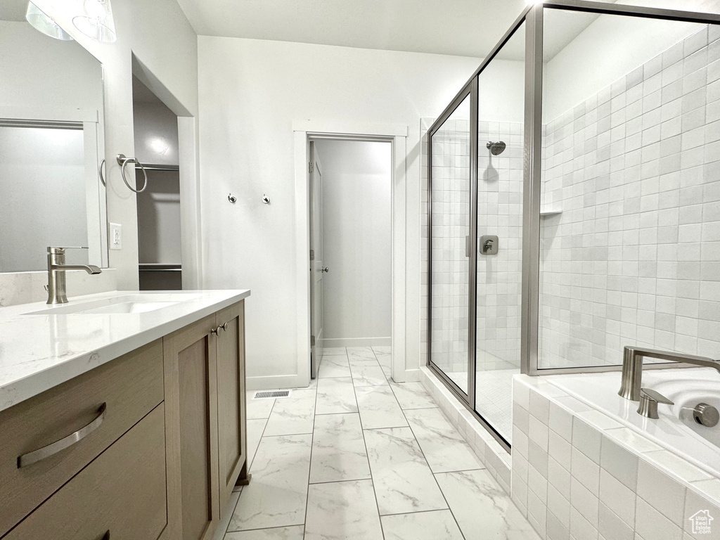 Bathroom with marble finish flooring, a stall shower, a garden tub, and vanity