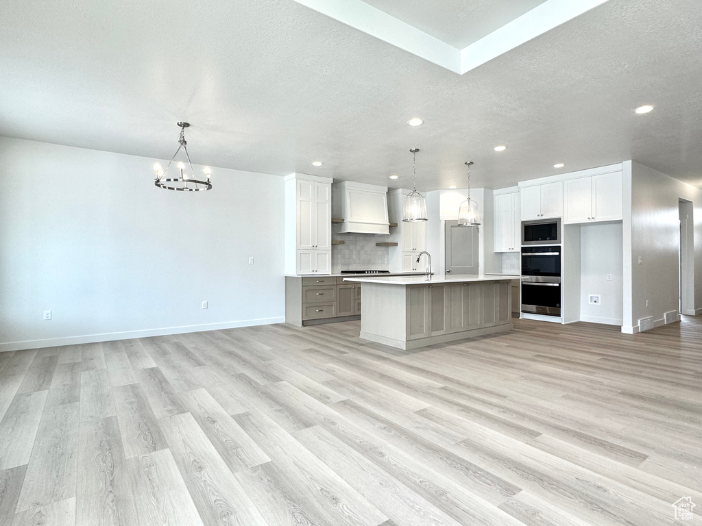 Kitchen featuring appliances with stainless steel finishes, recessed lighting, a chandelier, open floor plan, and light wood finished floors