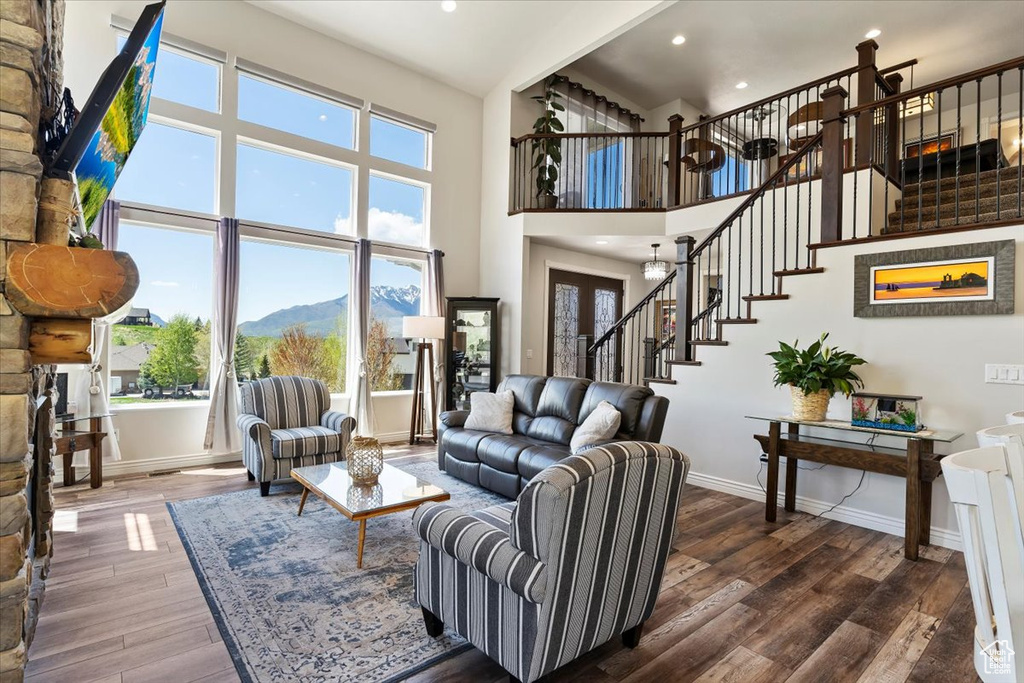 Living area with stairs, hardwood / wood-style floors, baseboards, recessed lighting, and a high ceiling