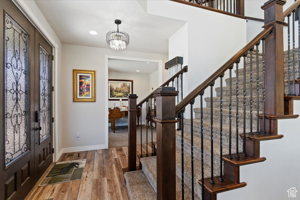 Foyer featuring wood-type flooring, stairs, baseboards, a chandelier, and recessed lighting