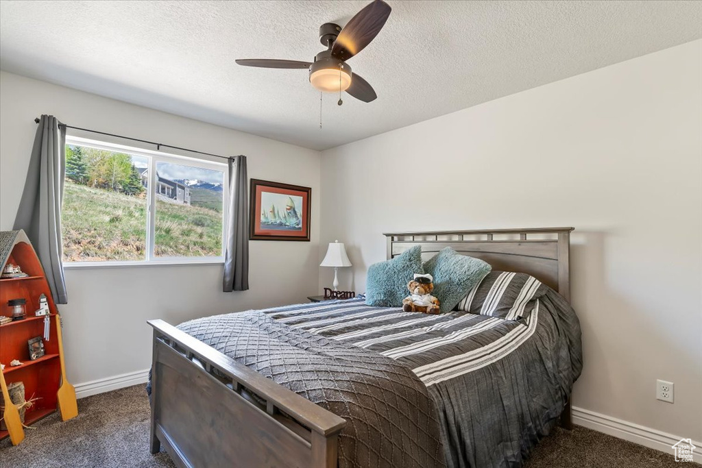 Bedroom featuring carpet floors, baseboards, ceiling fan, and a textured ceiling