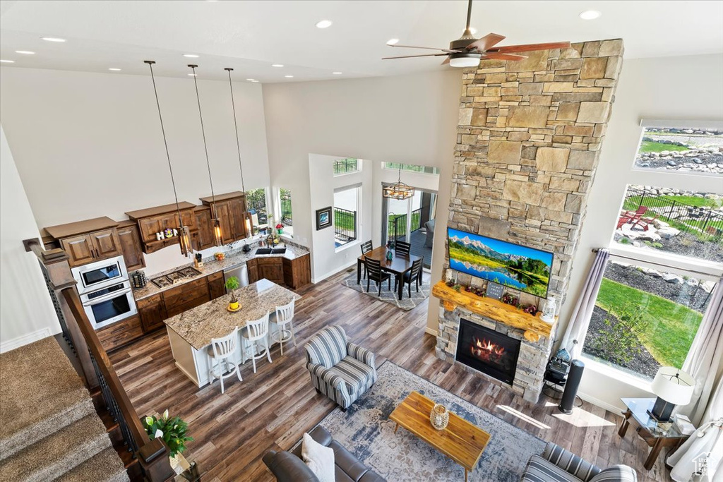 Living room featuring high vaulted ceiling, a stone fireplace, a ceiling fan, healthy amount of natural light, and recessed lighting
