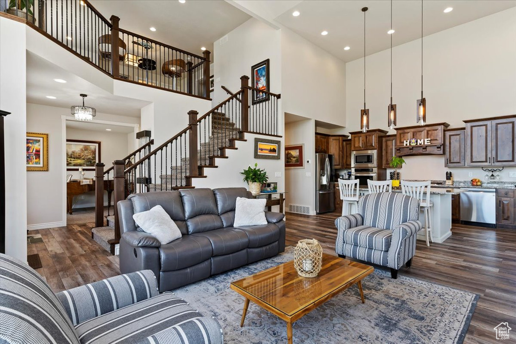 Living area with a towering ceiling, baseboards, dark wood finished floors, stairway, and recessed lighting