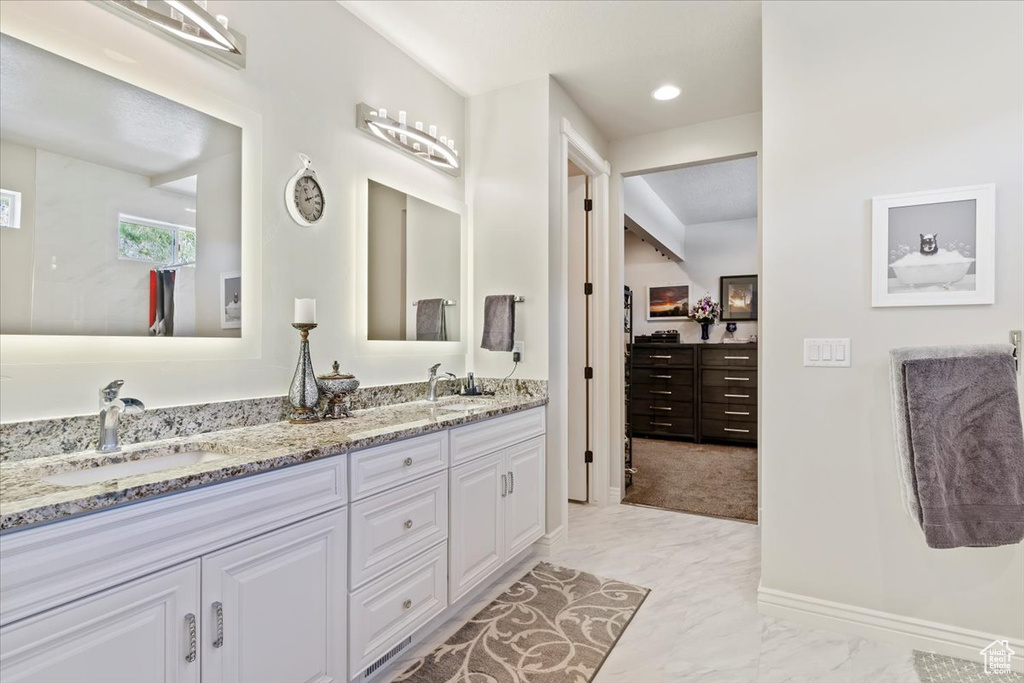 Full bath with marble finish floors, double vanity, and baseboards