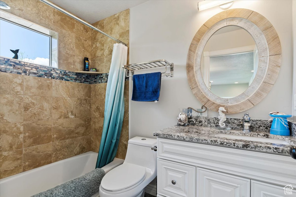 Full bathroom featuring toilet, shower / bathtub combination with curtain, and vanity