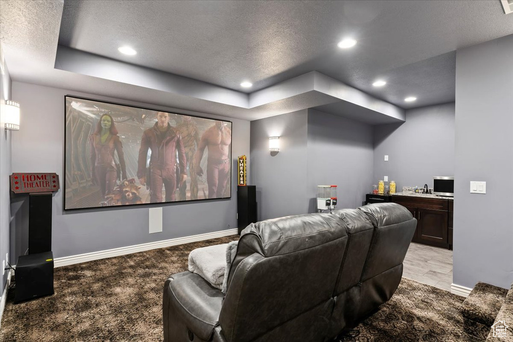 Cinema with a textured ceiling, recessed lighting, baseboards, a bar, and light colored carpet