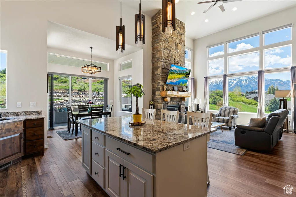 Kitchen featuring a towering ceiling, dark wood-type flooring, a fireplace, ceiling fan, and healthy amount of natural light