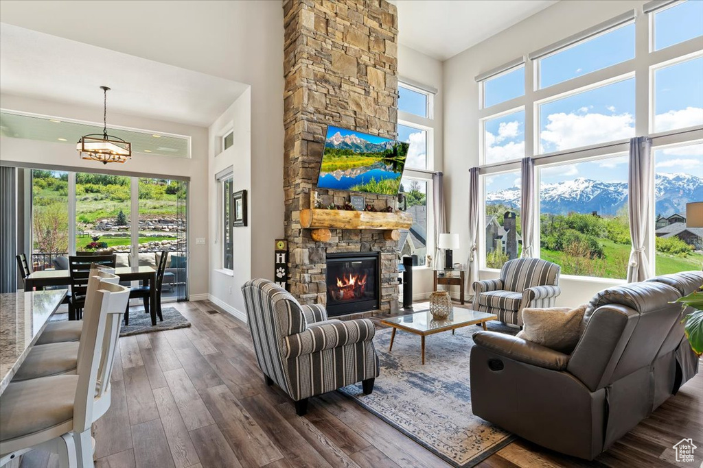 Living area with a towering ceiling, dark wood finished floors, a stone fireplace, a chandelier, and baseboards