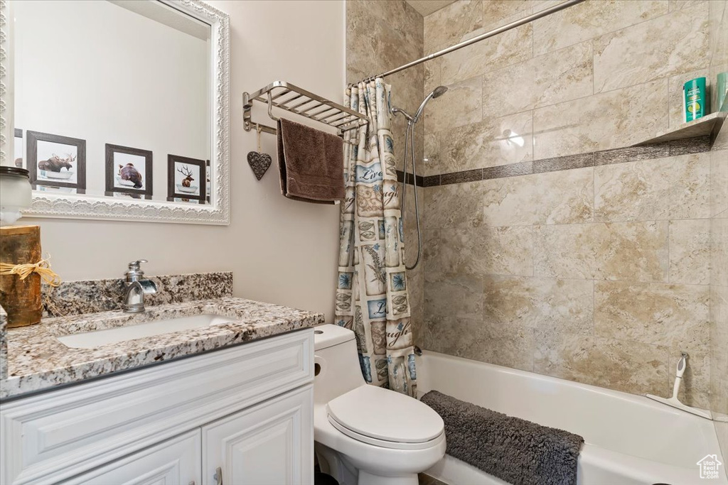 Bathroom featuring toilet, vanity, and shower / tub combo with curtain