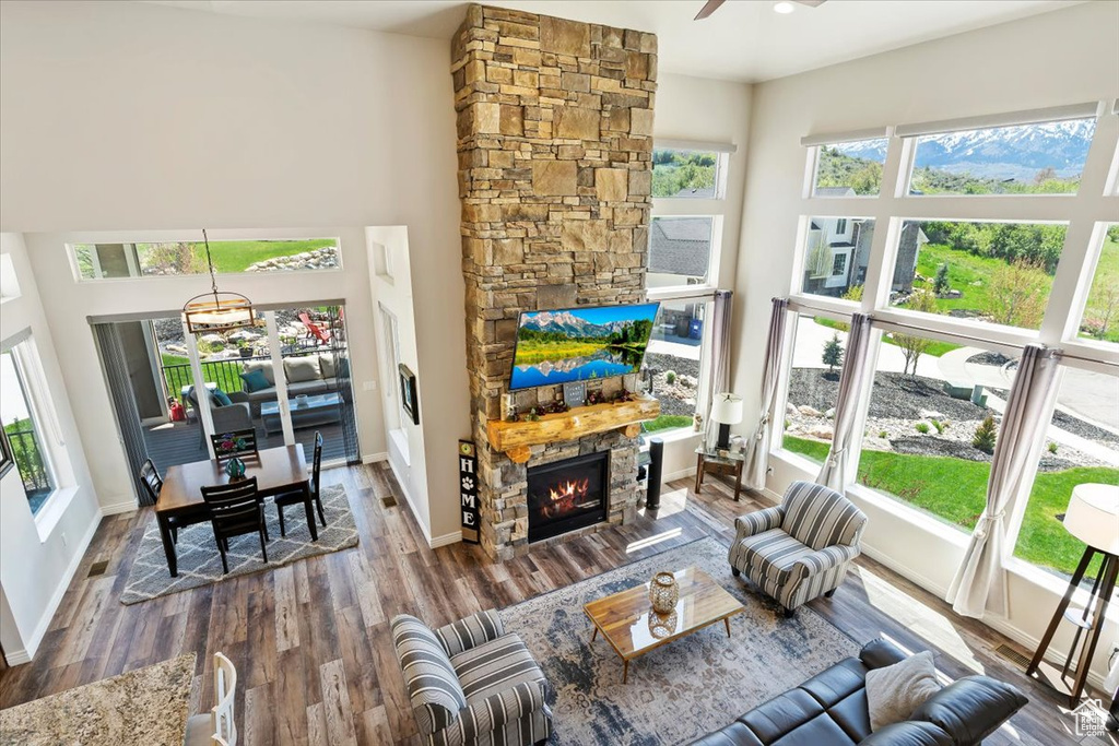 Living area with a fireplace, dark wood finished floors, a ceiling fan, baseboards, and a chandelier