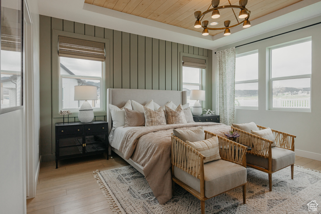 Bedroom featuring a chandelier, light wood finished floors, a raised ceiling, baseboards, and wooden ceiling