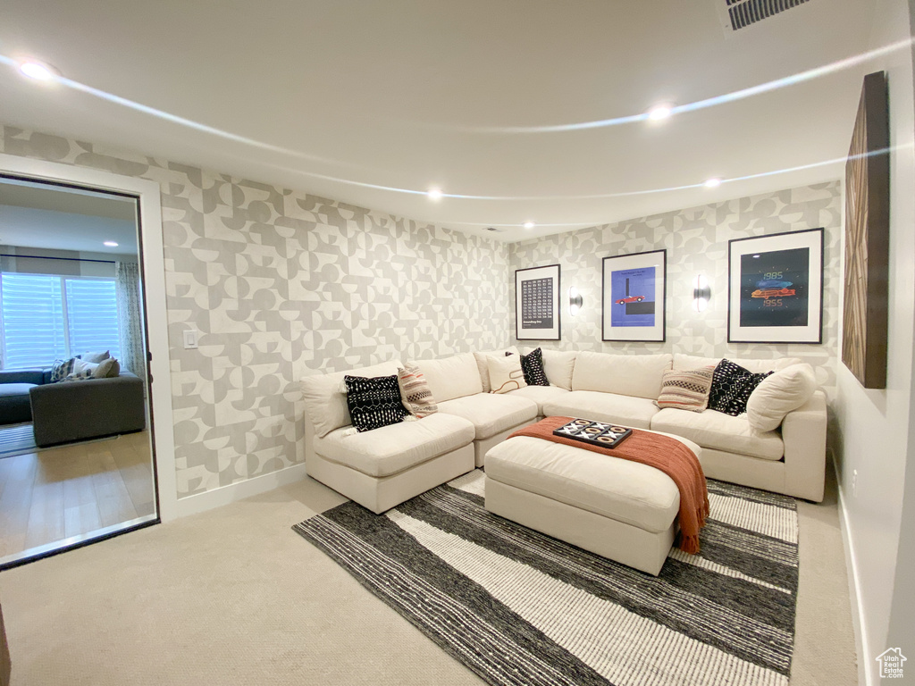 Carpeted living room with wallpapered walls, baseboards, and recessed lighting