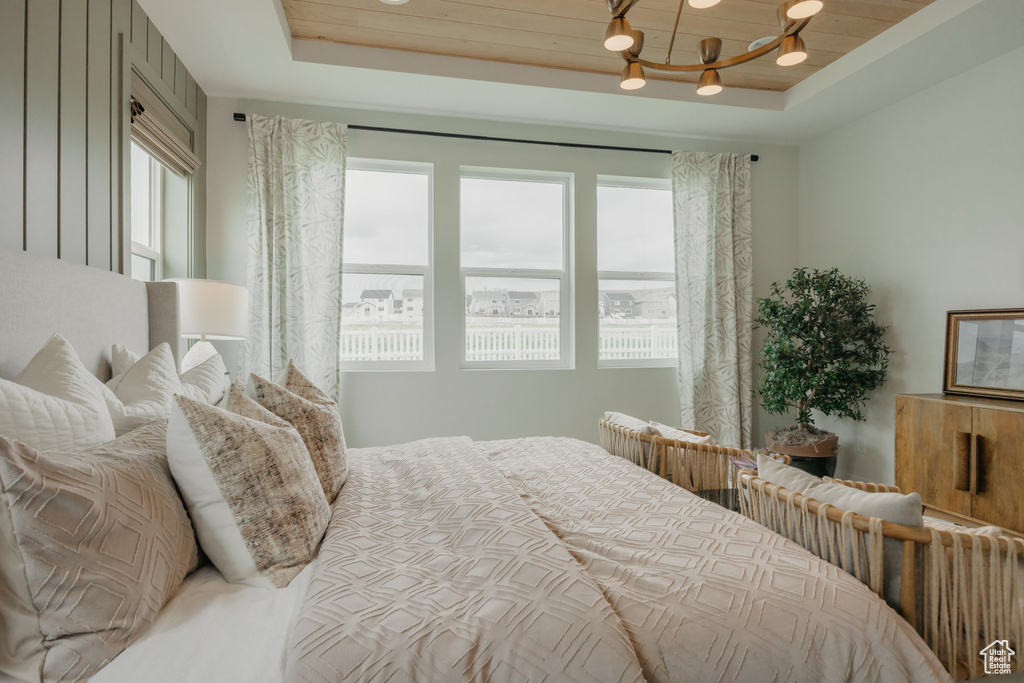 Bedroom featuring a raised ceiling and a chandelier