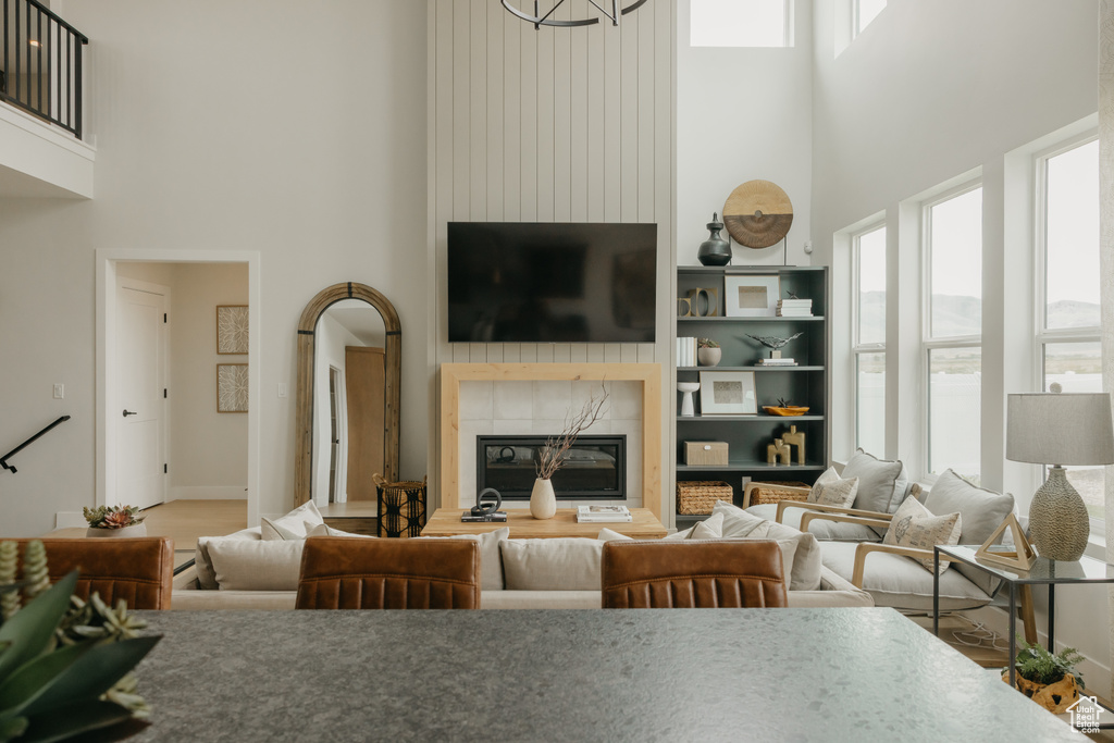 Living room with a high ceiling, a tiled fireplace, and baseboards