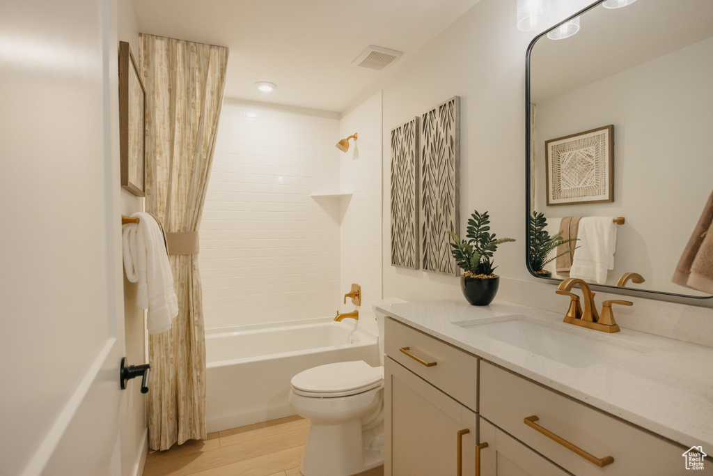 Bathroom with toilet, vanity, shower / bath combination with curtain, and wood finished floors