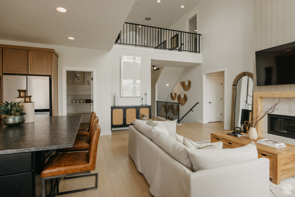 Living area featuring light wood-style floors, a high end fireplace, recessed lighting, a towering ceiling, and baseboards