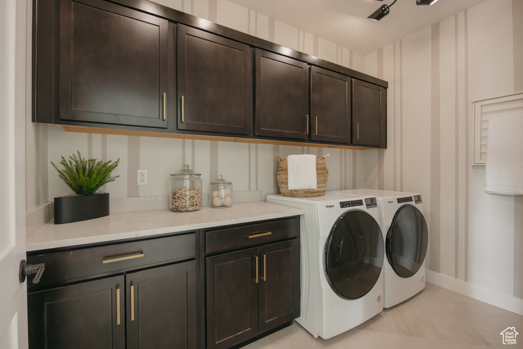 Washroom featuring cabinet space, washing machine and clothes dryer, and baseboards
