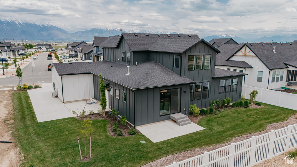 Rear view of property featuring board and batten siding, a residential view, a shingled roof, and a patio