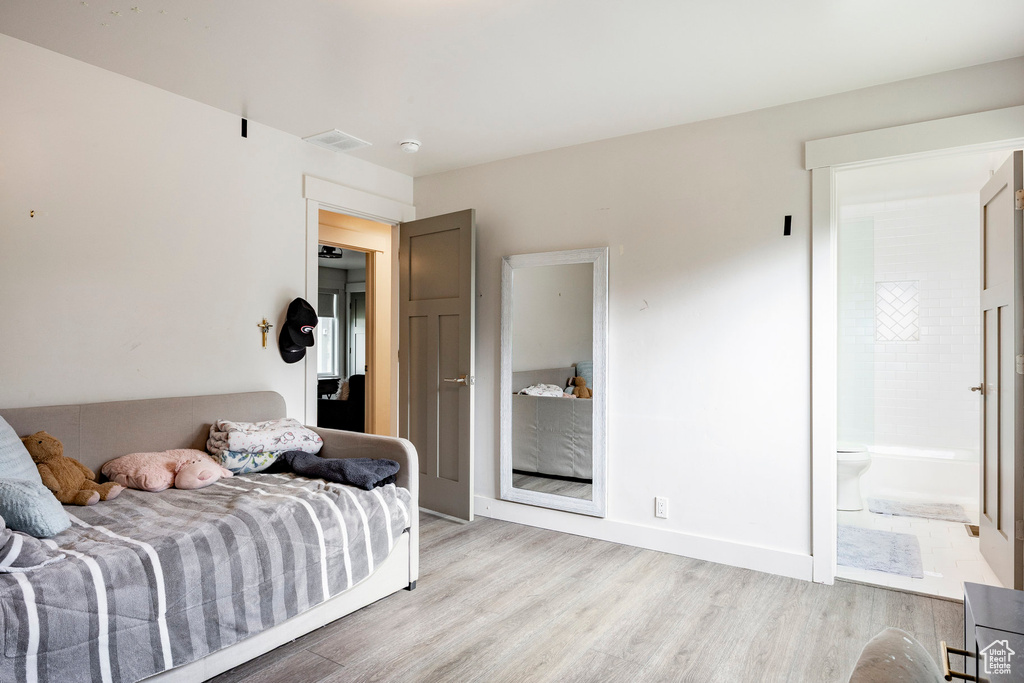 Bedroom featuring light wood-style floors and ensuite bath