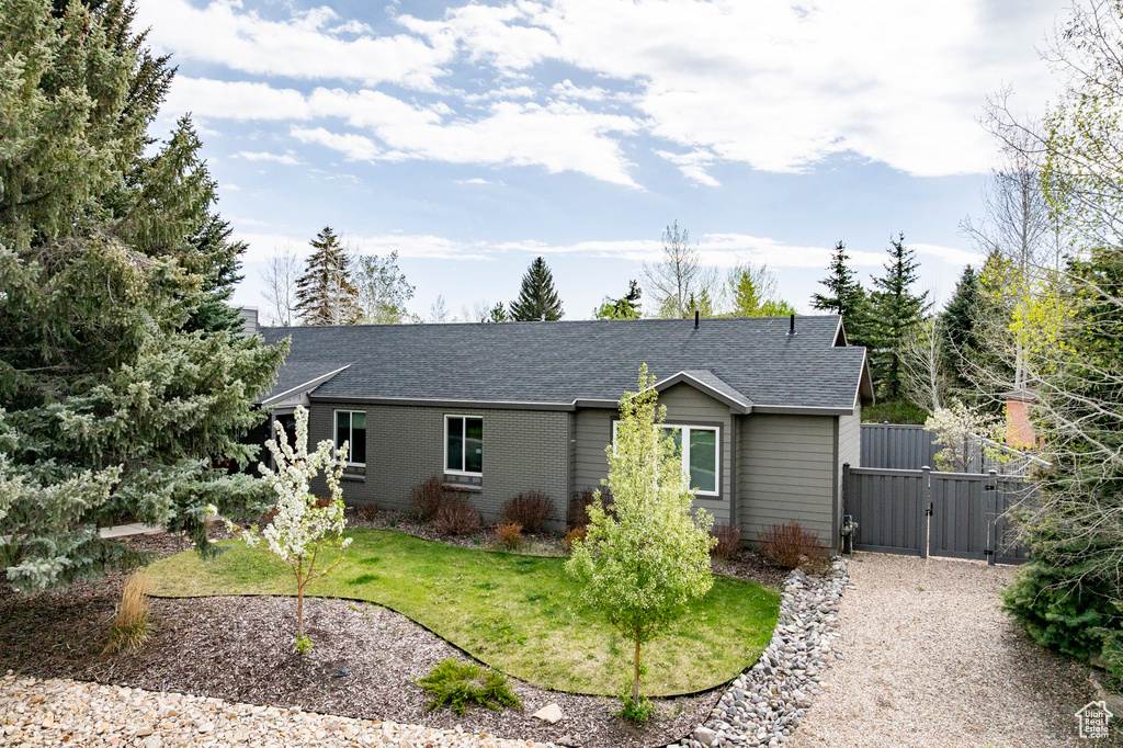 Single story home with a gate, roof with shingles, and a front lawn