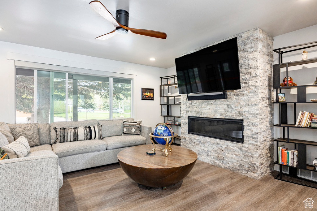 Living area with a ceiling fan, wood finished floors, and a fireplace