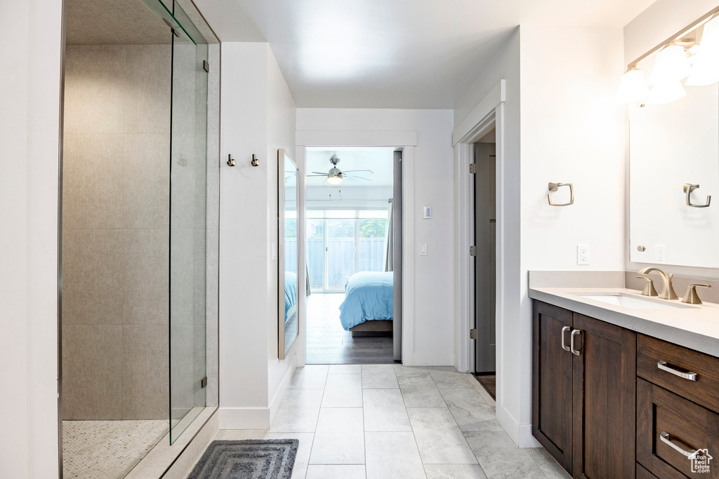 Ensuite bathroom with a stall shower, ceiling fan, vanity, tile patterned flooring, and baseboards