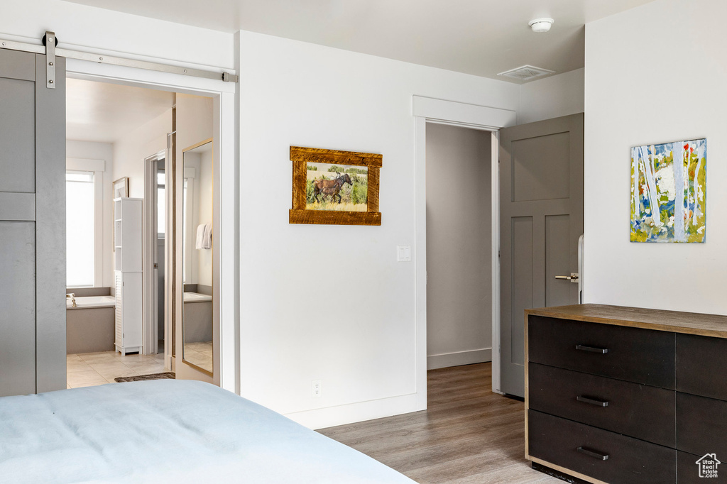 Bedroom with light wood-type flooring, ensuite bathroom, and baseboards