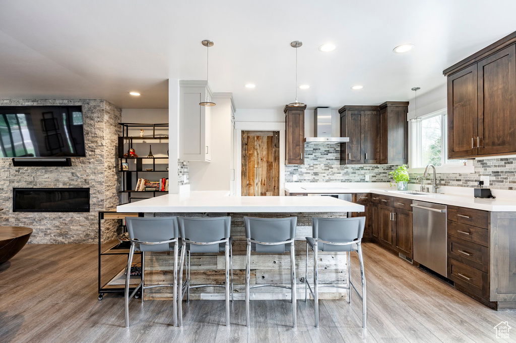 Kitchen featuring stainless steel dishwasher, a sink, dark brown cabinetry, a kitchen bar, and recessed lighting