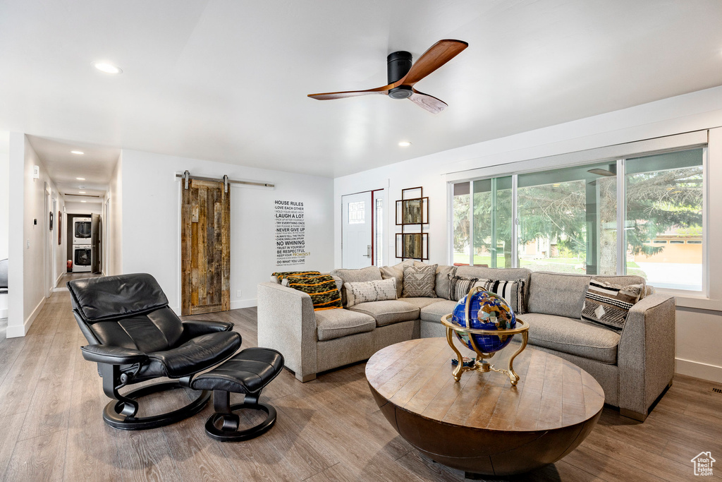 Living area with a barn door, ceiling fan, light wood-style flooring, baseboards, and recessed lighting