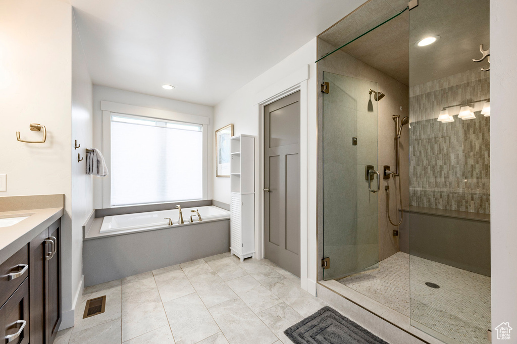 Full bath with a stall shower, a bath, vanity, and recessed lighting