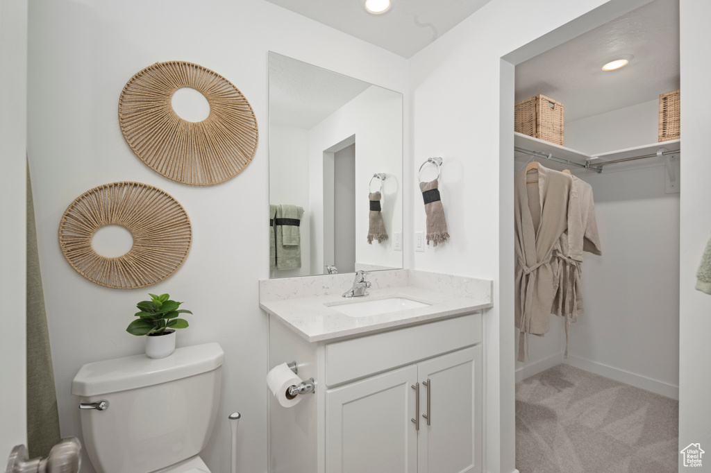 Bathroom featuring toilet, vanity, baseboards, and recessed lighting