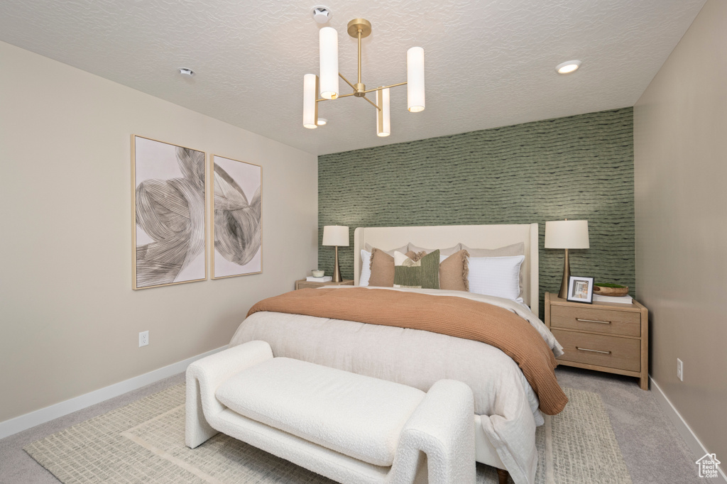 Bedroom featuring a chandelier, carpet floors, baseboards, an accent wall, and a textured ceiling