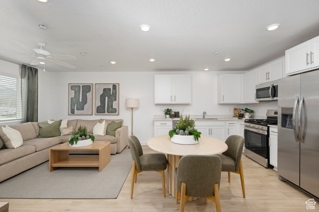 Kitchen with stainless steel appliances, a sink, open floor plan, white cabinets, and recessed lighting