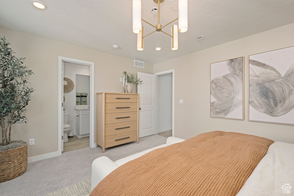 Bedroom with light colored carpet, baseboards, recessed lighting, ensuite bath, and a textured ceiling