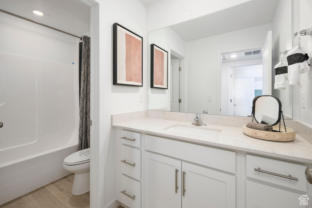 Bathroom with toilet, vanity, wood finished floors, and shower / bath combo
