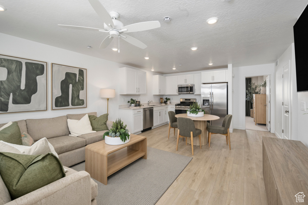 Living room featuring recessed lighting, a ceiling fan, light wood finished floors, and a textured ceiling