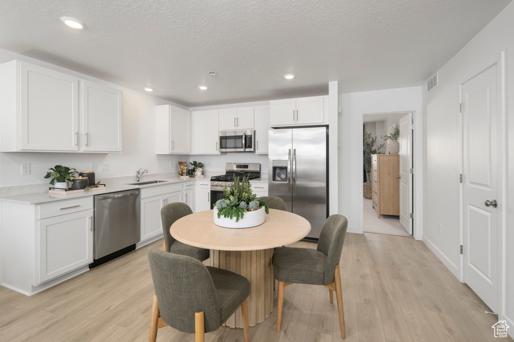 Kitchen featuring stainless steel appliances, a sink, light wood-type flooring, white cabinets, and recessed lighting