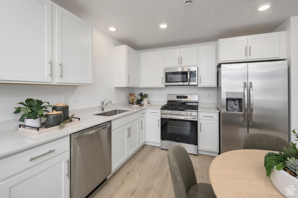 Kitchen featuring appliances with stainless steel finishes, a sink, white cabinets, and recessed lighting