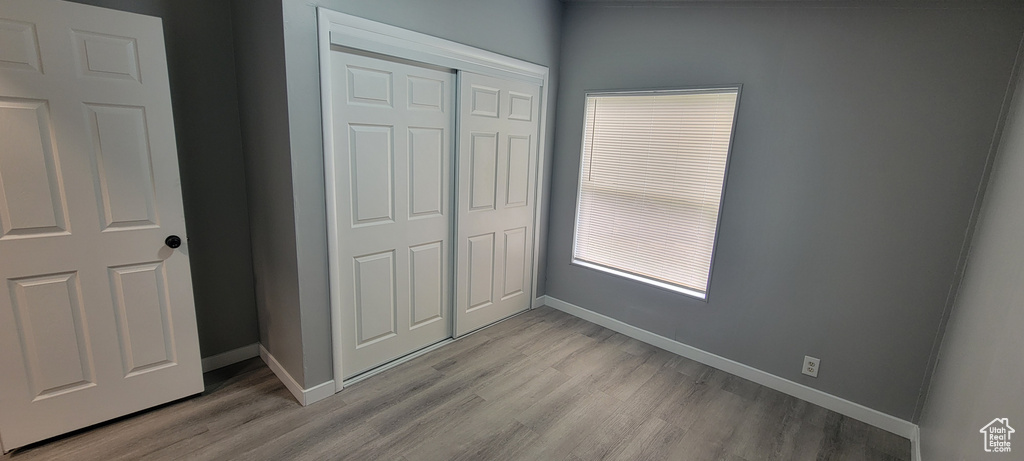 Unfurnished bedroom with light wood-style flooring, baseboards, and a closet