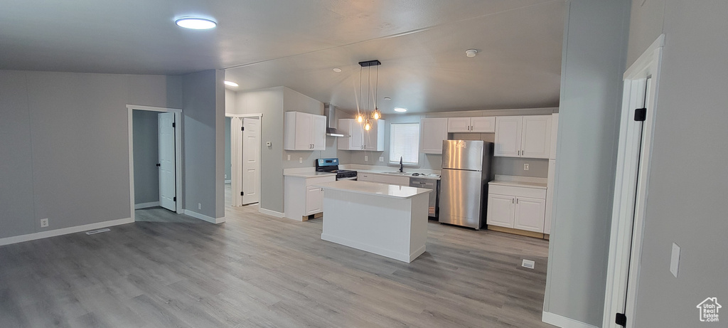 Kitchen featuring light wood-style flooring, a sink, wall chimney range hood, light countertops, and appliances with stainless steel finishes