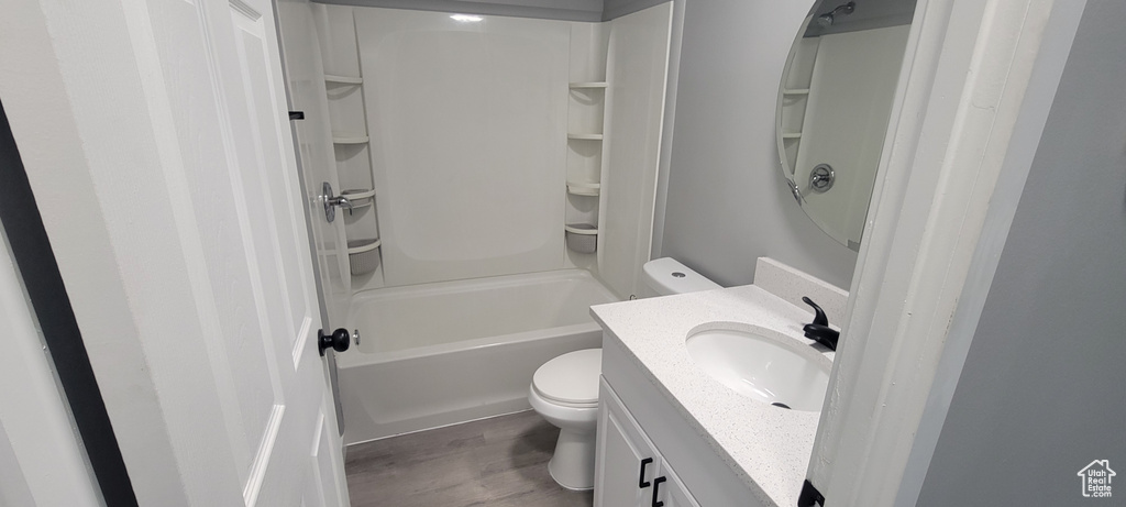 Bathroom with toilet, tub / shower combination, wood finished floors, and vanity