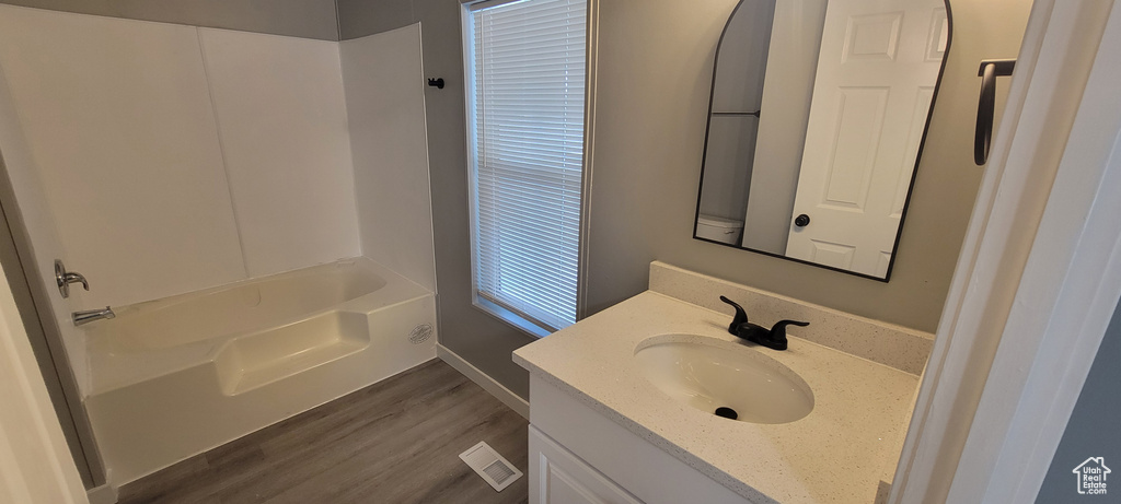 Full bathroom featuring shower / washtub combination, wood finished floors, vanity, visible vents, and baseboards