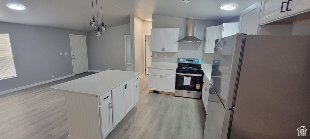 Kitchen featuring white cabinets, wall chimney exhaust hood, stainless steel appliances, and light wood-type flooring