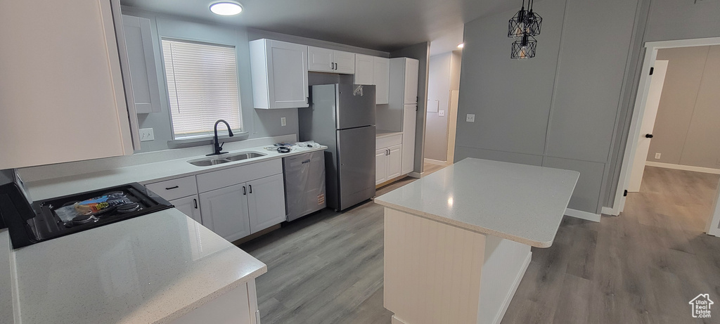 Kitchen with a sink, freestanding refrigerator, dishwashing machine, and light wood-style floors