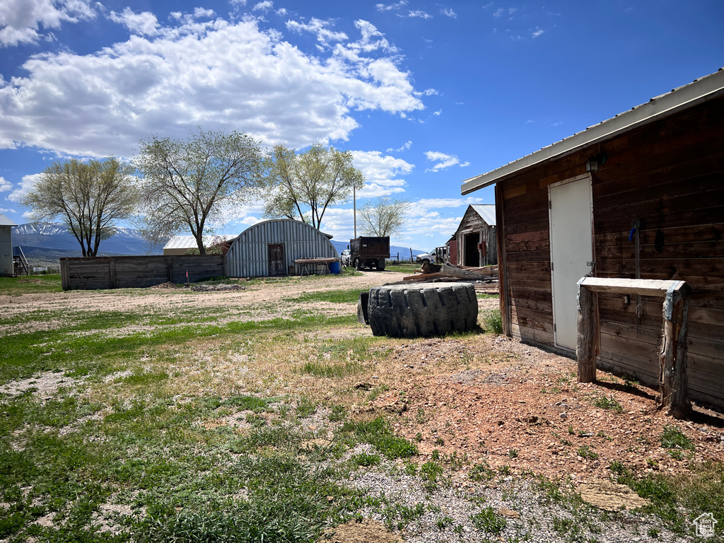 View of yard featuring an outdoor structure, a pole building, and fence