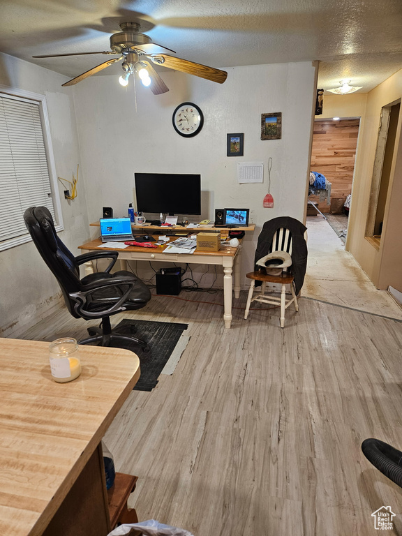 Living area featuring a ceiling fan, wood finished floors, an office area, and a textured ceiling